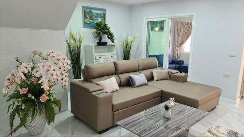 a living room with a brown couch and flowers at GORGEOUS NEW DESIGNED 4br KataBeach sweetHome in Kata Beach