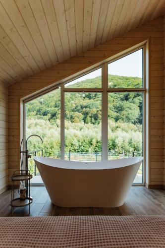 a bath tub in a room with a large window at Rika chalet in Stantsiya Dembina