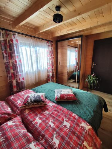 a bedroom with a bed with red and green sheets at domek przy Jodłowej in Niesulice