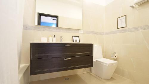 a bathroom with a sink and a toilet and a mirror at Villa De Shalom in Ocho Rios