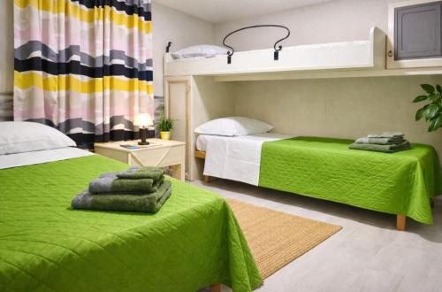 a bedroom with two beds with green sheets and a green blanket at VILLA DEI CICAS in Taranto