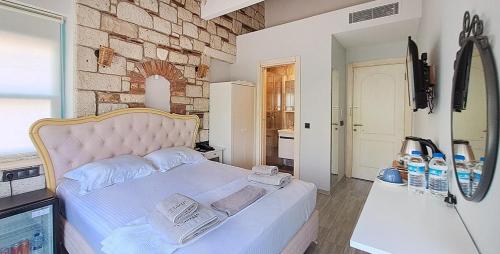 a bedroom with a white bed with a brick wall at Bellezza Hotel Alaçatı in Alaçatı