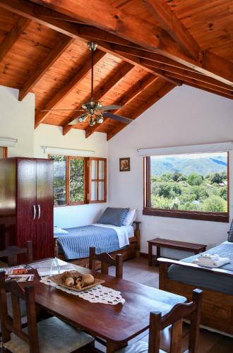 a living room with a table and a bed and a window at Complejo Falda del Sauce in Villa General Belgrano