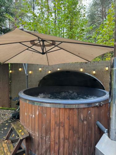 a large hot tub with an umbrella on top of it at Chata przy lesie - sauna i balia in Łuka