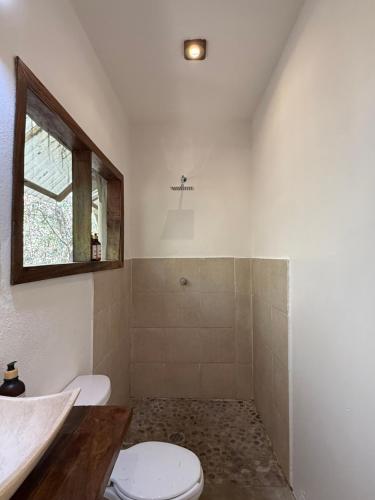 a bathroom with a toilet and a sink and a window at La baxada in Mazunte