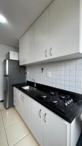 a kitchen with white cabinets and a black counter top at Flat Premium no Centro Tudo a Pé in Montes Claros