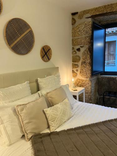 a bedroom with a bed with white sheets and pillows at Senhora da Estrela AL in Seia