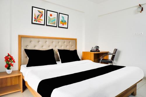 a bedroom with a large white bed with black pillows at Super Townhouse Lohegaon Near Pune Airport Formerly Landmark Regency in Pune