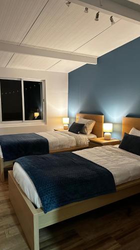two beds in a room with blue walls and windows at Azores Square House historic city center in Ponta Delgada