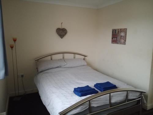 a bedroom with a bed with two blue towels on it at Noglas in Ammanford