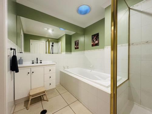 a white bathroom with a tub and a sink at Solara Retreat Mildura in Mildura