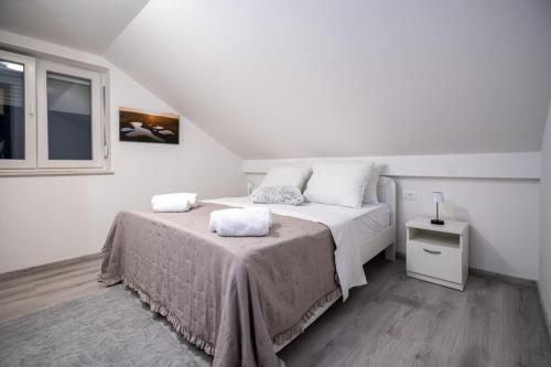 a white bedroom with two beds and a window at Fort Vista in Knin