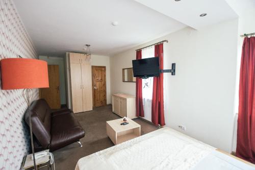a room with a bed and a chair and a television at Svečių namai Lingės in Nemėžis