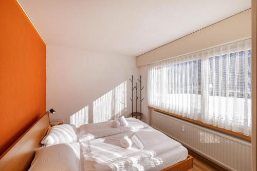 a bedroom with a bed and two windows at Brentsch A30 in Scuol