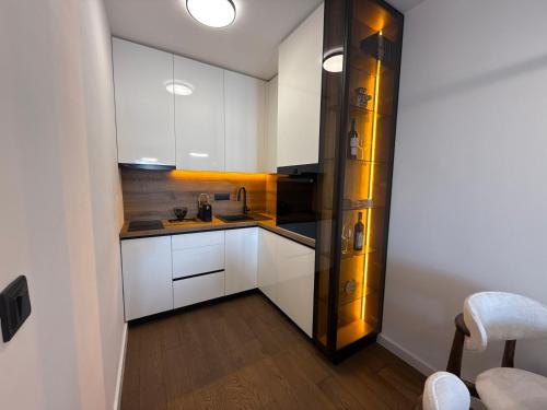 a kitchen with white cabinets and a wooden floor at Seafront apartment Tivat in Donja Lastva