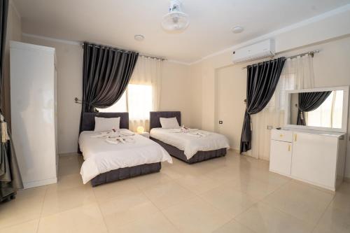 two beds in a room with two windows at siriuspalaceluxor in Al Karnak