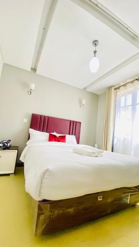 a bedroom with a large bed with a red headboard at Urban Host Buru Prime 1BR Luxe in Nairobi
