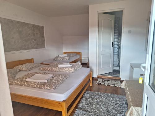 two beds in a small room with a bathroom at Rajni Panzió in Praid
