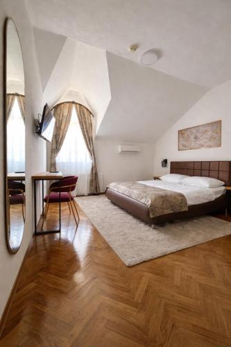 a bedroom with a bed and a table and a mirror at Motel Marić in Žepče