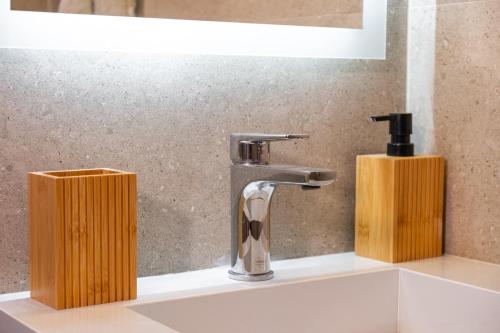 a bathroom sink with a faucet and two soap dispensers at Mary's cozy apartment 2 in Pýrgos
