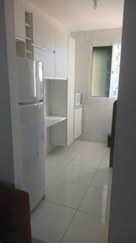 a white kitchen with a refrigerator and a window at Apto mobiliado 7min da Orla de Atalaia e 1min do Aeroporto in Aracaju