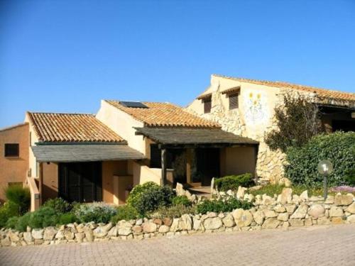 a house with a stone wall next to a building at CASA MUGHETTO R5055 WiFi, seafront, private sea access, swimming pool in La Maddalena