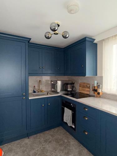 a blue kitchen with white counter tops and blue cabinets at Soho Skyline Apartment - 360 views of landmarks in London