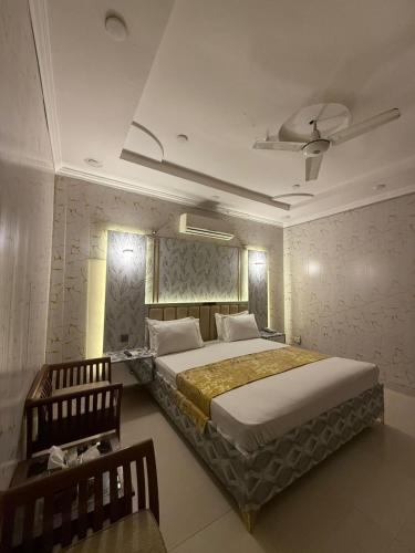 a bedroom with a large bed and a chair at The Lodge Inn in Karachi