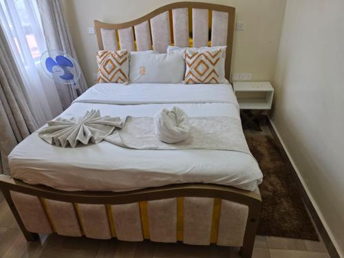 a bedroom with a large bed with white sheets and pillows at Jay Homes - Modern & Cozy Apartments PGS Plaza - Nakuru CBD in Nakuru