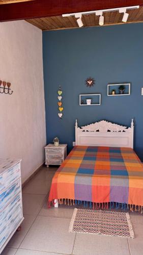 a bedroom with a bed and a blue wall at Chácara Pôr do sol in Alfenas