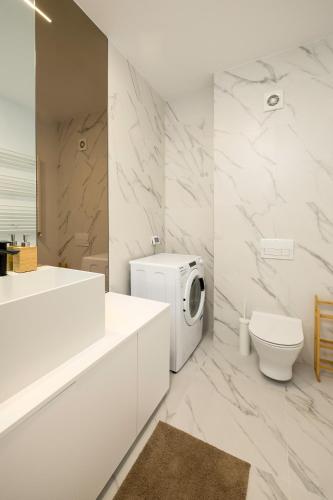 a white bathroom with a toilet and a sink at Lila Residence - by Solinis Homes in Bucharest