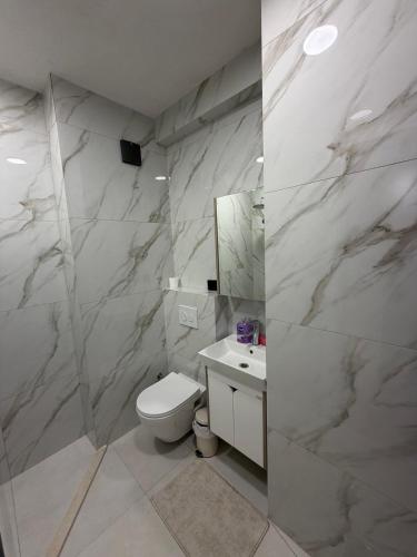 a white bathroom with a toilet and a sink at ZONE apartments in Prishtinë