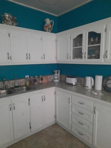une cuisine avec des armoires blanches et un mur bleu dans l'établissement Jude Apartments, à Soufrière
