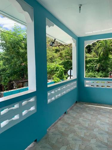 une pièce avec deux fenêtres et un mur bleu dans l'établissement Jude Apartments, à Soufrière