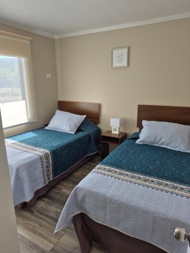 a hotel room with two beds and a window at Cabañas San Luis in Colbún