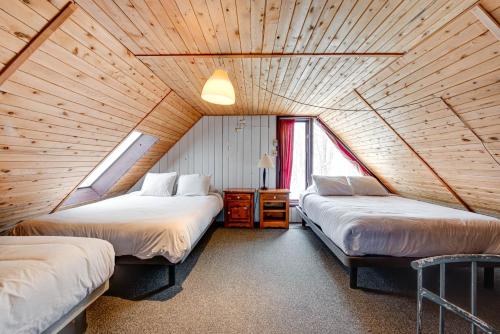 two beds in a room with a wooden ceiling at Mountain View 148 - 4 chambres - 13 personnes in Beaupré