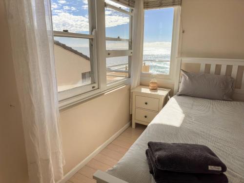 a bedroom with a bed and a window with the ocean at Sunny Apt on The Esplanade - Aircon in Cronulla