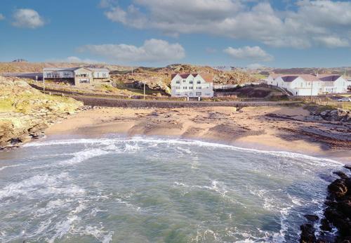 a view of a beach with houses and the ocean at GWYNFA-3 BED- GROUND FLOOR APT - SEA VIEWS - TREARDDUR BAY in Trearddur