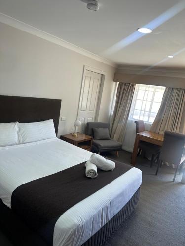 a bedroom with a bed and a desk and a chair at The Aston Motel Tamworth in Tamworth