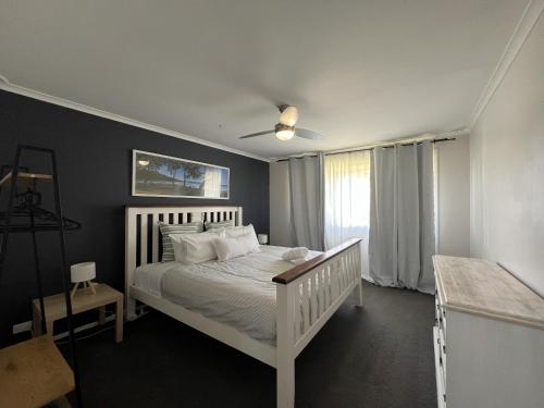 a bedroom with a white bed with a ceiling fan at Southern Comfort in Esperance in Esperance