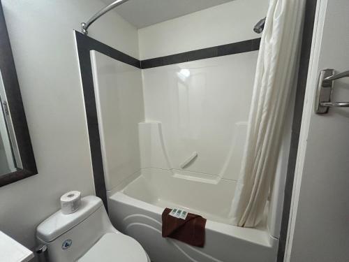 a white bathroom with a toilet and a shower at Northern Lights Inn & Suites in Valleyview