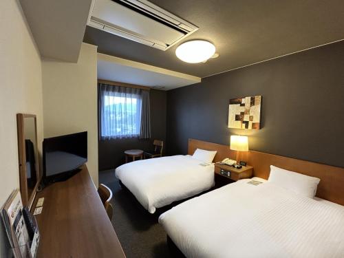 a hotel room with two beds and a television at Hotel Route-Inn Shin Gotemba Inter -Kokudo 246 gou- in Gotemba