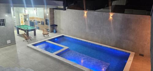 a swimming pool in the middle of a room with a table at Pousada Coisa Nossa - Praia Cibratel II - 200m da praia in Itanhaém