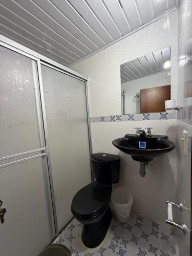 a bathroom with a black toilet and a sink at Casa Sué Soatá in Soatá