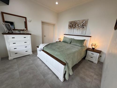 a bedroom with a white bed and a dresser at Taipa Coastal Retreat in Taipa
