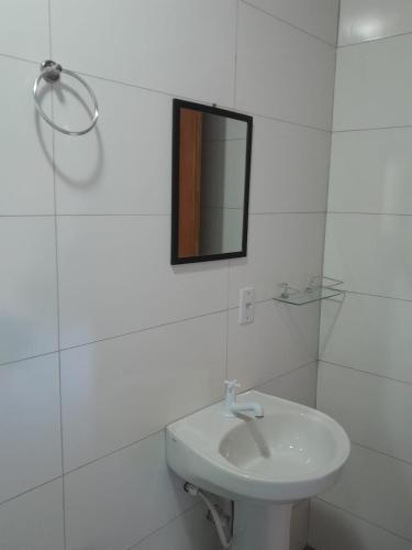 a white bathroom with a sink and a mirror at ResidencialBambu2 in Garopaba