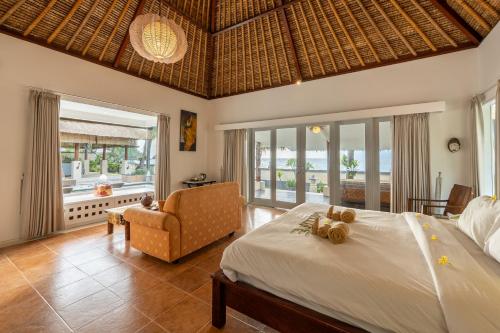 ein Schlafzimmer mit Bett, Stuhl und Fenstern in der Unterkunft Puri Mas Boutique Resort & Spa in Senggigi 