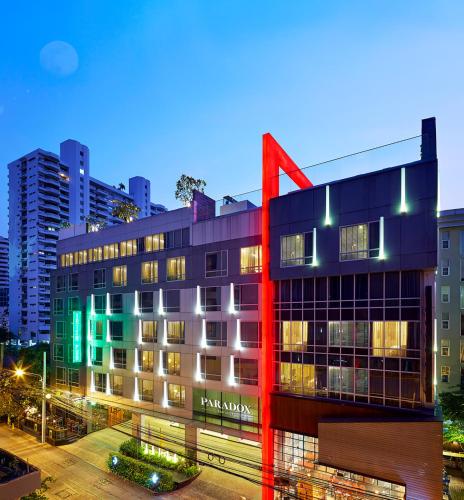 a building with a red structure in front of a city at Paradox Bangkok Sukhumvit in Bangkok