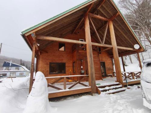 a log cabin in the snow with a snowman at 源泉ログの宿 in Sobetsu