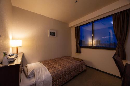 a hotel room with a bed and a window at ホテルグランフォーレ in Shikokuchuo